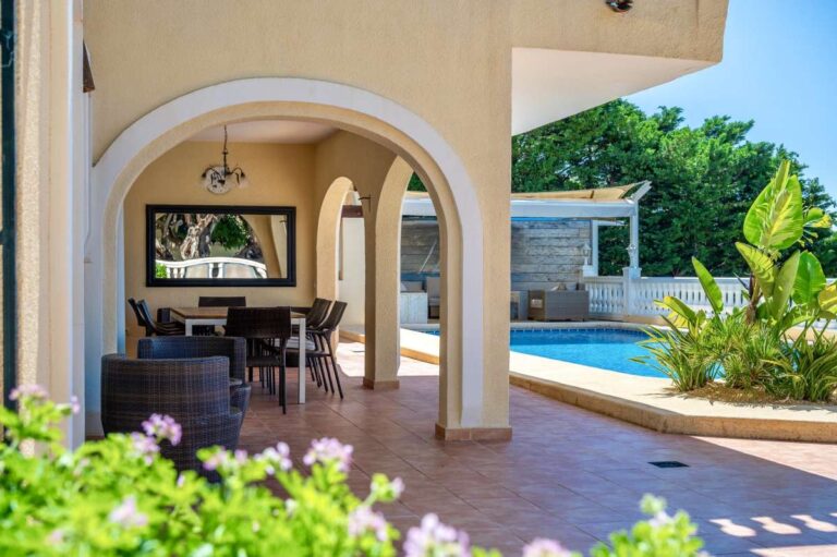 Covered terrace at an elegant Mediterranean villa in Altea Hills with arched openings, pool access and outdoor seating area