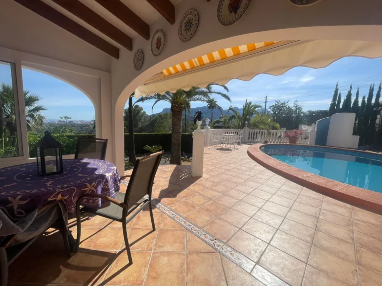 Covered terrace beside the private swimming pool with outdoor dining space at a villa in Calpe.