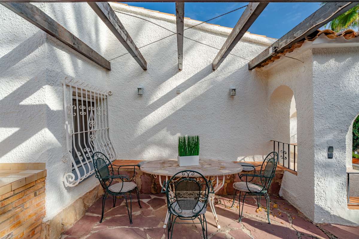 Covered terrace dining area with wooden beams and outdoor seating at a Mediterranean villa in Maryvilla, Calpe.