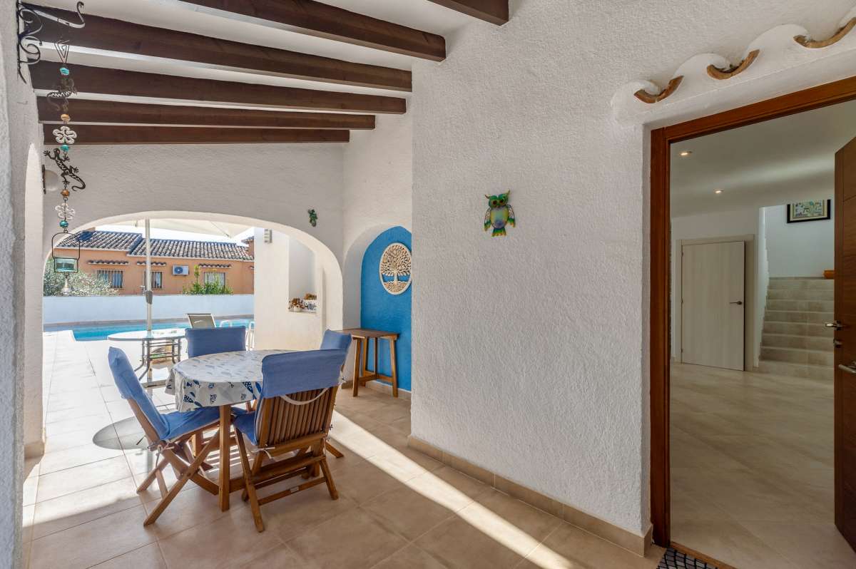 Covered terrace entrance with outdoor dining space at a contemporary villa in Calpe with private pool.