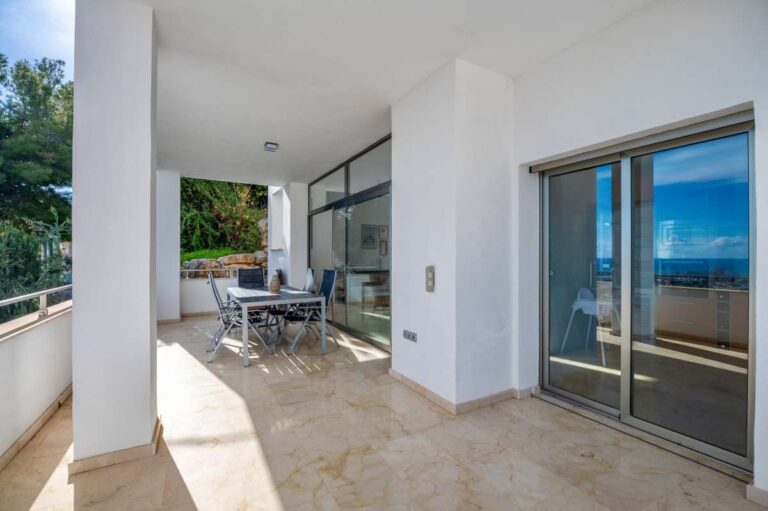 Covered terrace entrance with sliding glass doors and outdoor seating at a modern spacious villa in Calpe.