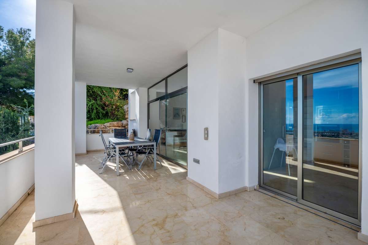 Covered terrace entrance with sliding glass doors and outdoor seating at a modern spacious villa in Calpe.