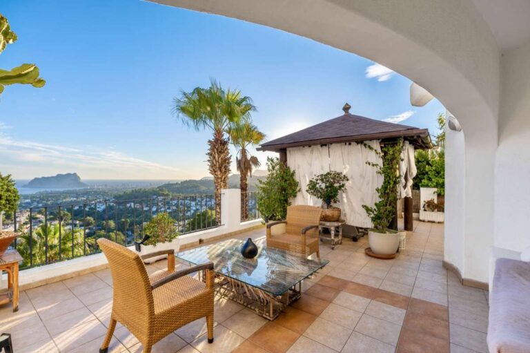 Covered terrace lounge at a villa in Benissa with outdoor seating, Mediterranean plants and panoramic views towards Calpe