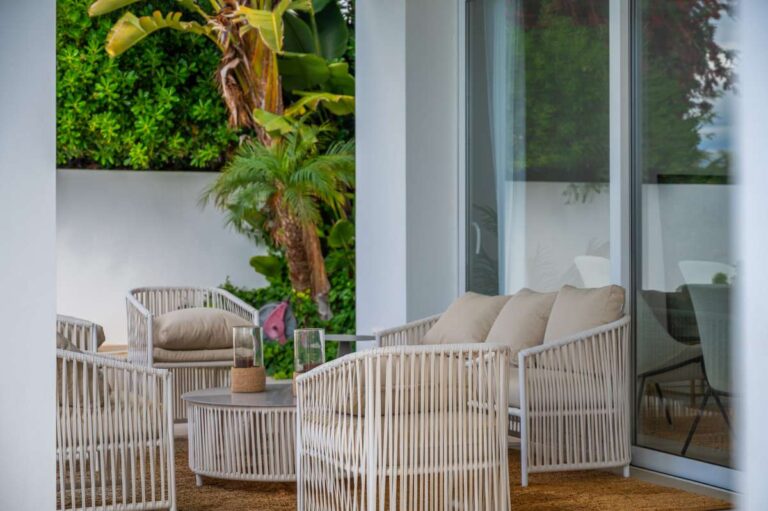 Covered terrace seating at a modern villa in Altea Hills with outdoor chairs, sliding doors, garden views and shaded lounge area