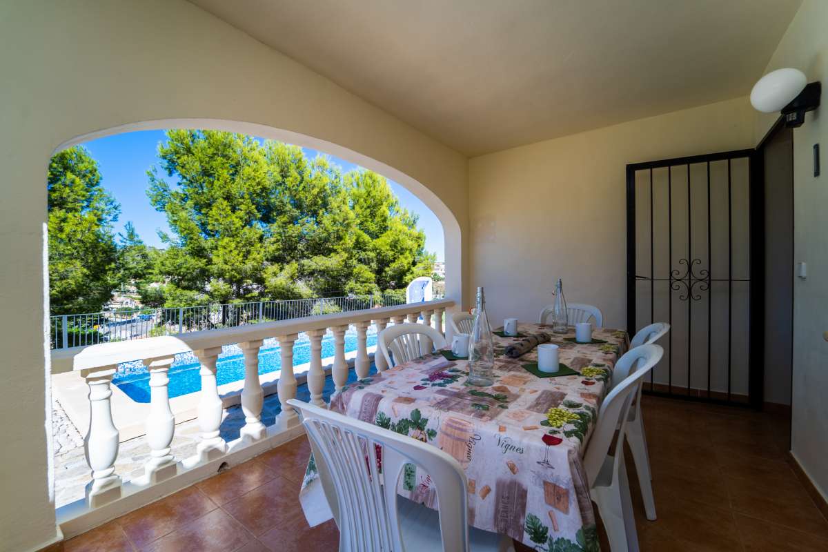 Covered terrace with outdoor dining area and garden views at a Mediterranean villa in Calpe.