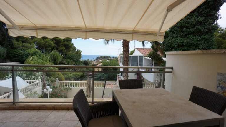 Covered terrace with outdoor dining space and sea views at a villa in La Fustera.