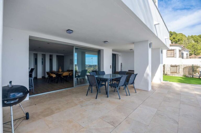 Covered terrace with outdoor seating beside the garden at a modern spacious villa in Calpe.