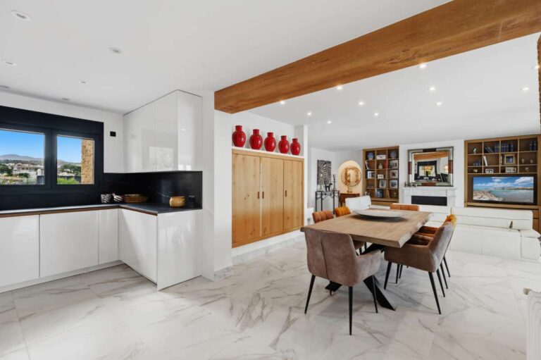 Dining area and kitchen inside a premium coastal villa on the Benissa Costa with modern white cabinetry, wooden dining table and bright open-plan layout