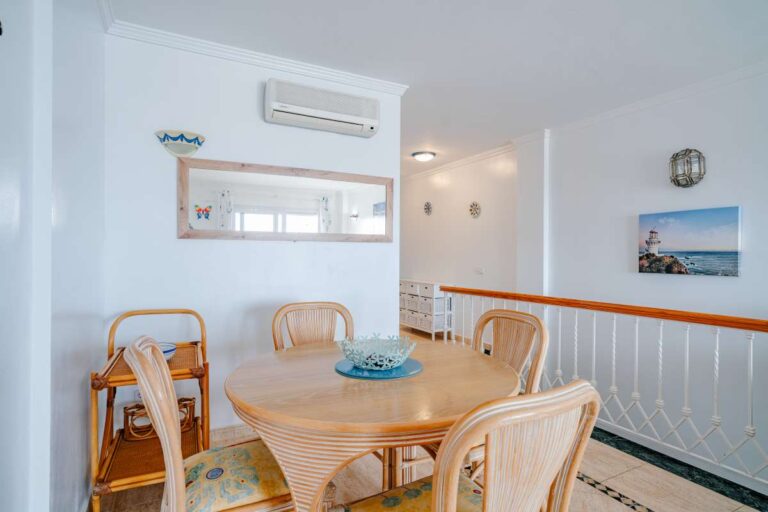 Dining area inside a duplex apartment near Les Platgetes Beach in Moraira with round dining table, staircase, air conditioning and bright interior