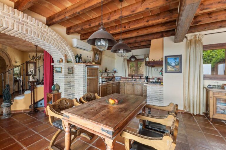 Dining area inside a finca-style villa in Benissa Costa with wooden beams, rustic kitchen, terracotta tiled floor and Mediterranean character