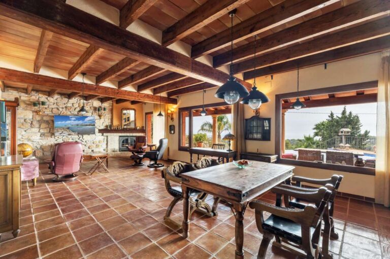 Dining area inside a finca-style villa in Benissa Costa with wooden beams, terracotta tiled floor, rustic furniture and sea views through large windows