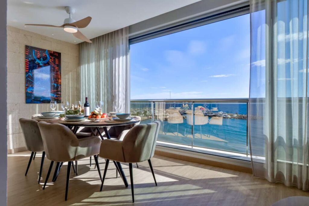 Dining area inside a luxury frontline beach duplex in Mascarat, Altea with large windows, terrace access and panoramic Mediterranean Sea views