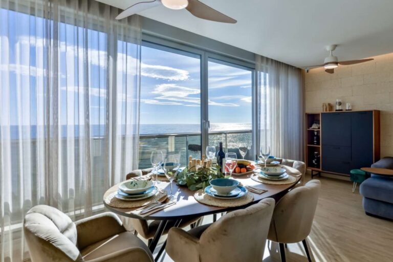 Dining area inside a luxury frontline beach duplex in Mascarat, Altea with large windows, terrace views and Mediterranean Sea views