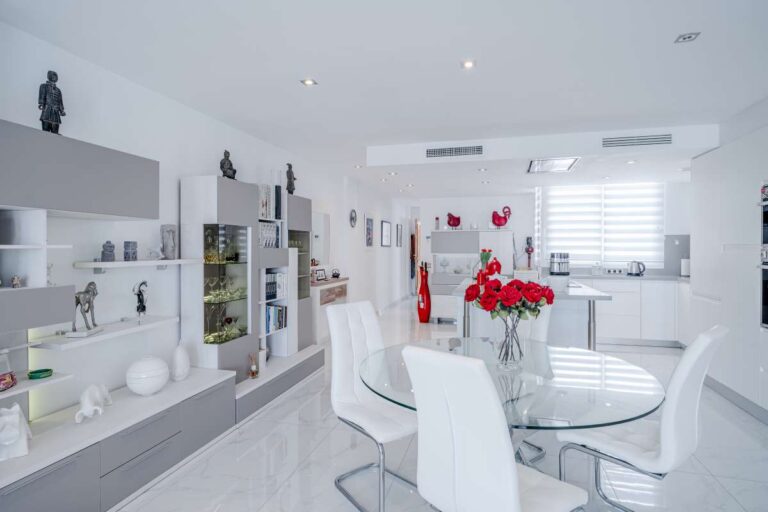 Dining area inside a renovated Arenal-Bol apartment in Calpe with built-in storage, white interiors and open-plan layout