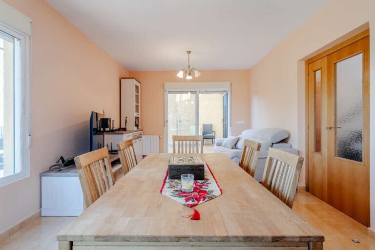 Dining area inside a semi-detached house in Calpe with wooden table, natural light and access towards the terrace
