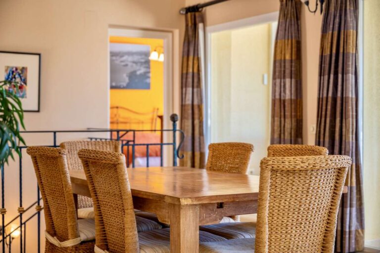Dining area inside an elegant Mediterranean villa in Altea Hills with wooden table, wicker chairs and terrace access nearby