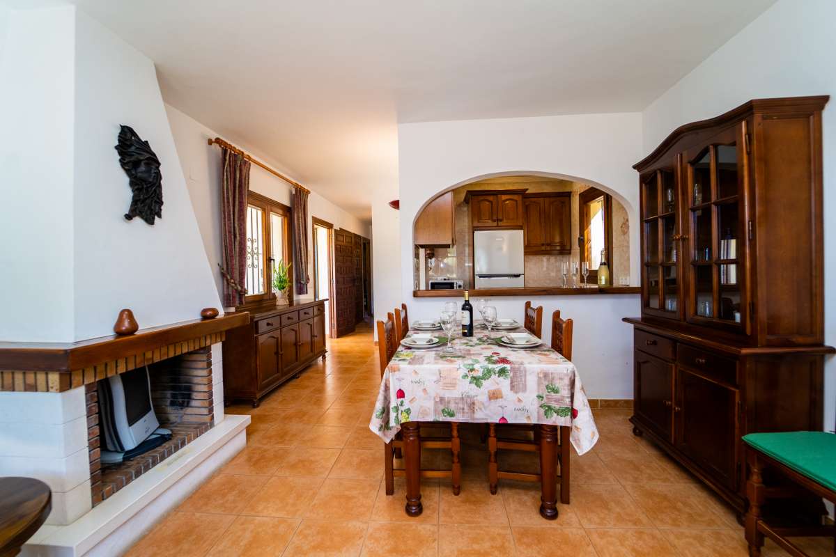 Dining area with fireplace, open kitchen and traditional furniture inside a Mediterranean villa in Cometa III, Calpe.
