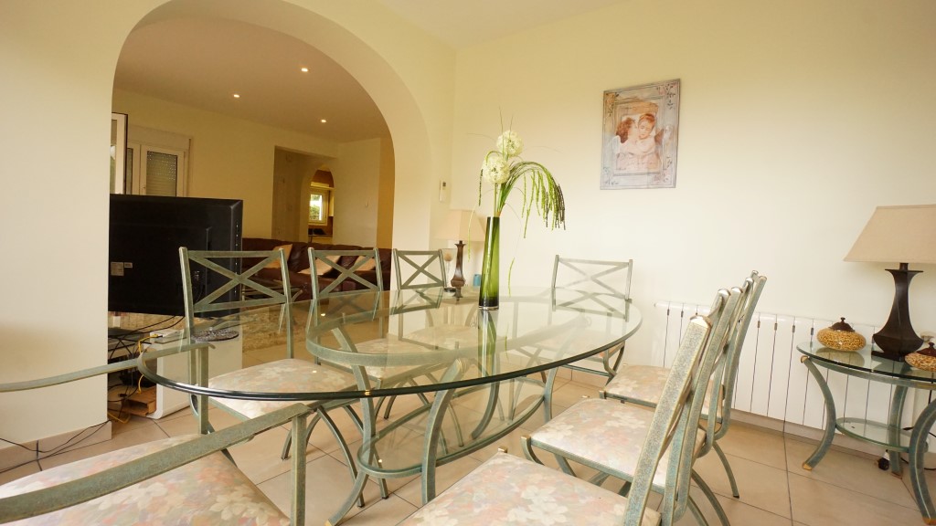 Dining area with glass table and arched opening inside a villa near La Fustera beach.