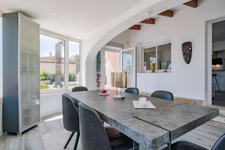 Dining area with open-plan kitchen and glazed terrace access inside a renovated Mediterranean villa in La Cometa, Calpe.