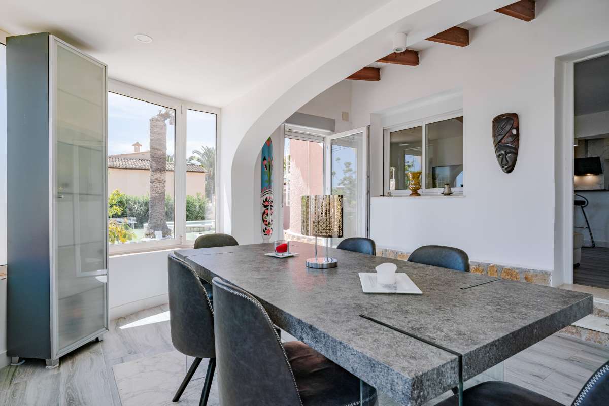 Dining area with open-plan kitchen and glazed terrace access inside a renovated Mediterranean villa in La Cometa, Calpe.