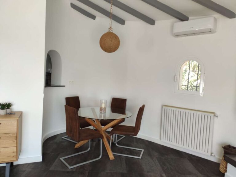 Dining area with traditional table, ceiling beams and radiator inside a refurbished villa in Canuta, Calpe.