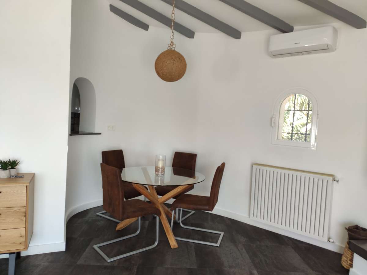 Dining area with traditional table, ceiling beams and radiator inside a refurbished villa in Canuta, Calpe.