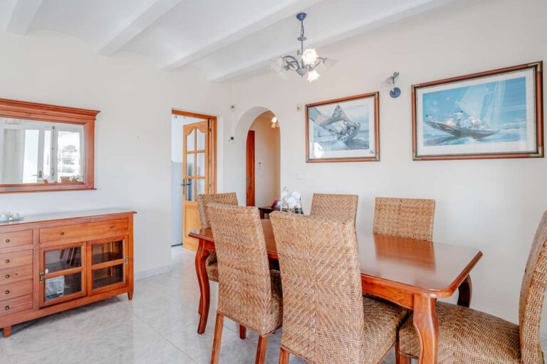 Dining area with traditional wooden furniture and arched doorway inside a Mediterranean villa with independent guest accommodation in Calpe.