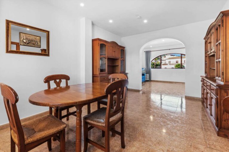 Dining area with wooden furniture and arched opening inside a guest apartment at a spacious villa in Calpe.