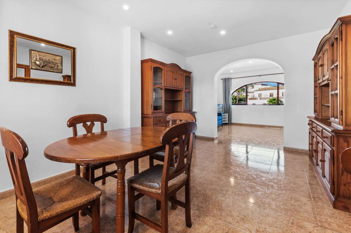 Dining area with wooden furniture and arched opening inside a guest apartment at a spacious villa in Calpe.