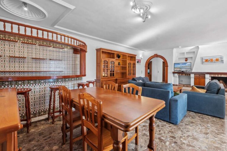 Dining area with wooden table and staircase inside a spacious villa with guest apartments in Calpe.