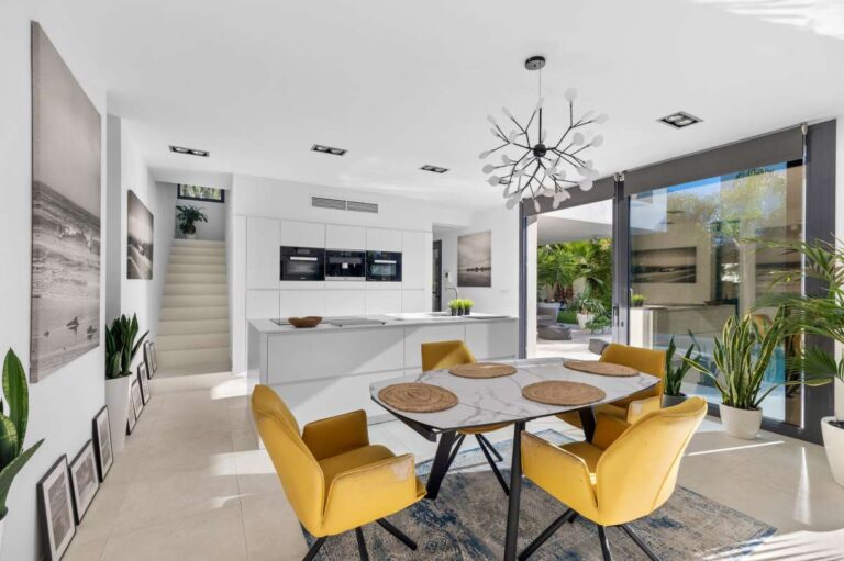 Dining area with yellow chairs, garden views and open-plan layout inside a modern oasis villa near Arenal-Bol Beach in Calpe.