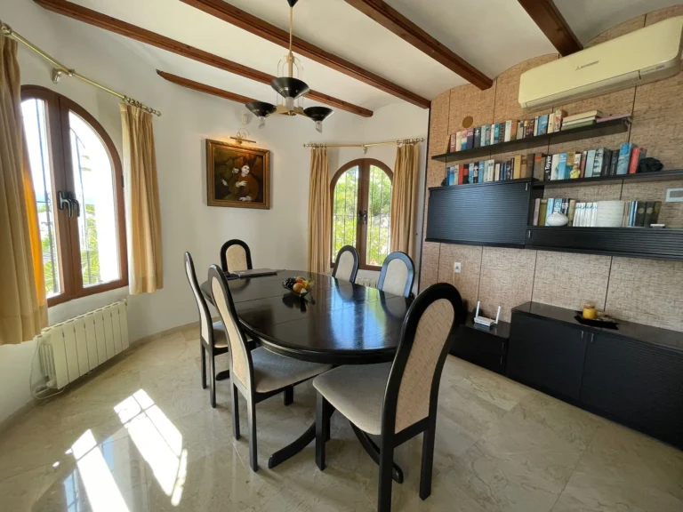 Dining room with built-in storage, wood-beamed ceiling, and natural light inside a villa in Calpe.