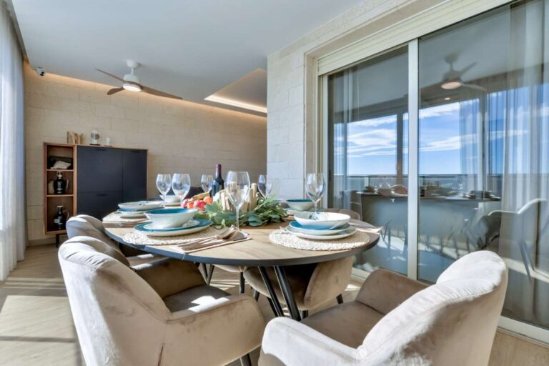 Dining table inside a luxury frontline beach duplex in Mascarat, Altea with panoramic sea views, terrace access and natural light