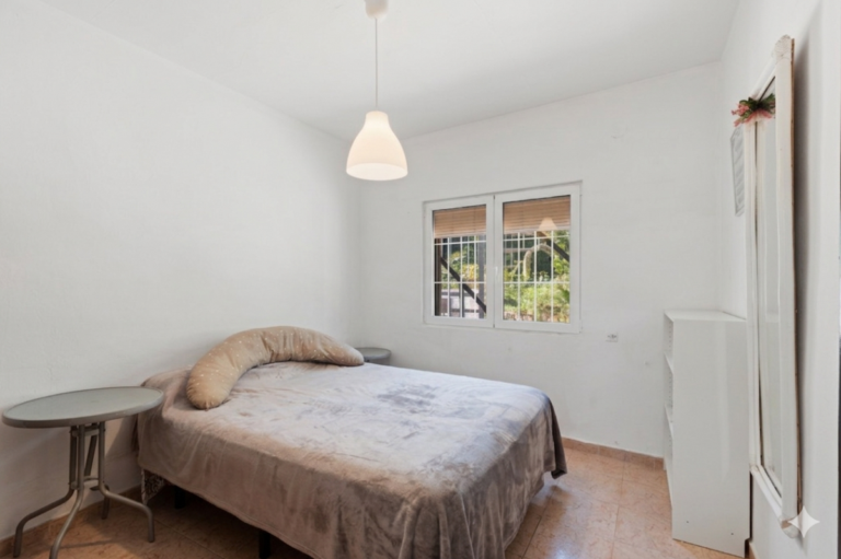 Double bedroom inside a Mediterranean villa in Benissa Costa with window, small table and simple bright interior layout