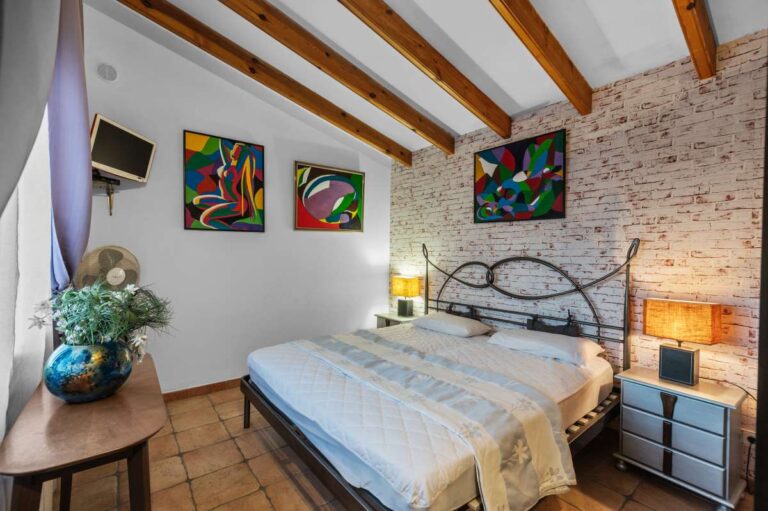 Double bedroom inside a panoramic sea view villa in Benissa with exposed stone wall, wooden beams and traditional Mediterranean character