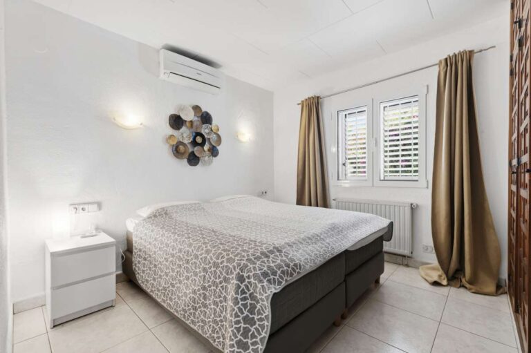 Double bedroom inside a renovated single-level villa in Moraira with air conditioning, shuttered windows, radiator and bright neutral finish