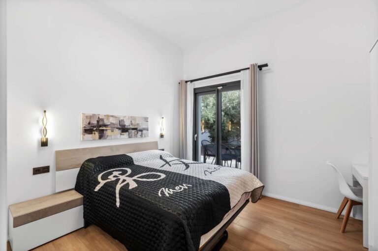 Double bedroom inside a single-level modern villa in Santa Clara, Altea with garden access, wood flooring, bedside lighting and contemporary finish