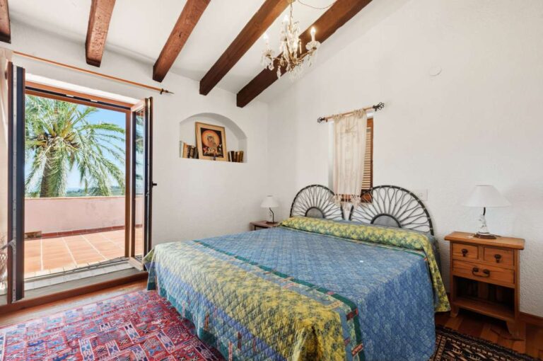 Double bedroom inside a traditional Spanish finca near Moraira with beamed ceiling, terrace access, wooden furniture and rustic Mediterranean style