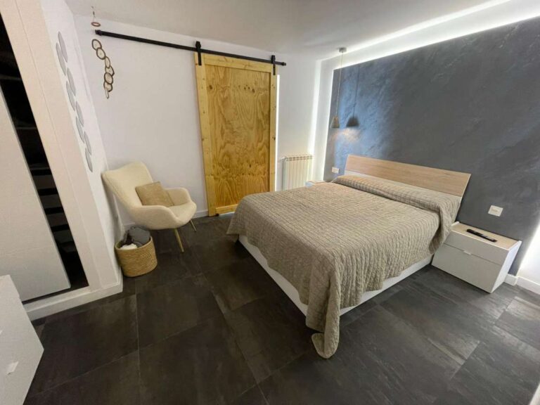 Double bedroom with feature wall, natural light and modern finishes inside a refurbished villa in Canuta, Calpe.