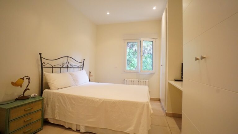 Double bedroom with fitted storage and natural light inside a villa near La Fustera beach.