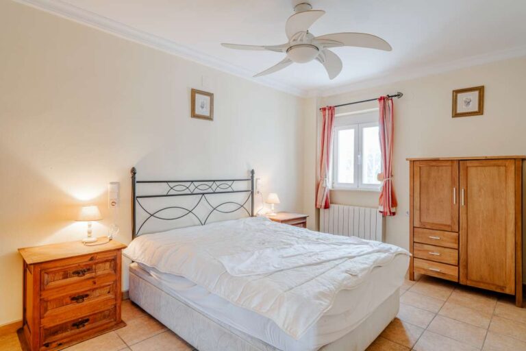 Double bedroom with traditional furniture, ceiling fan and natural light inside a Mediterranean villa in Calpe.