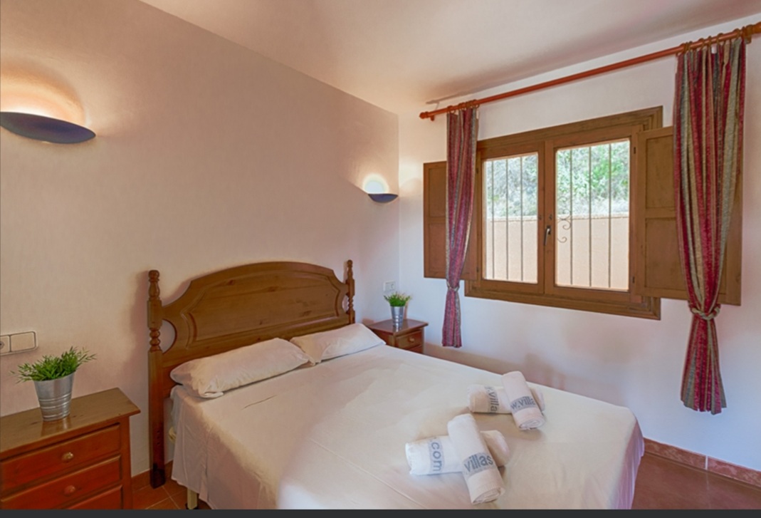 Double bedroom with traditional wooden furniture and natural light inside a Mediterranean villa in Calpe.