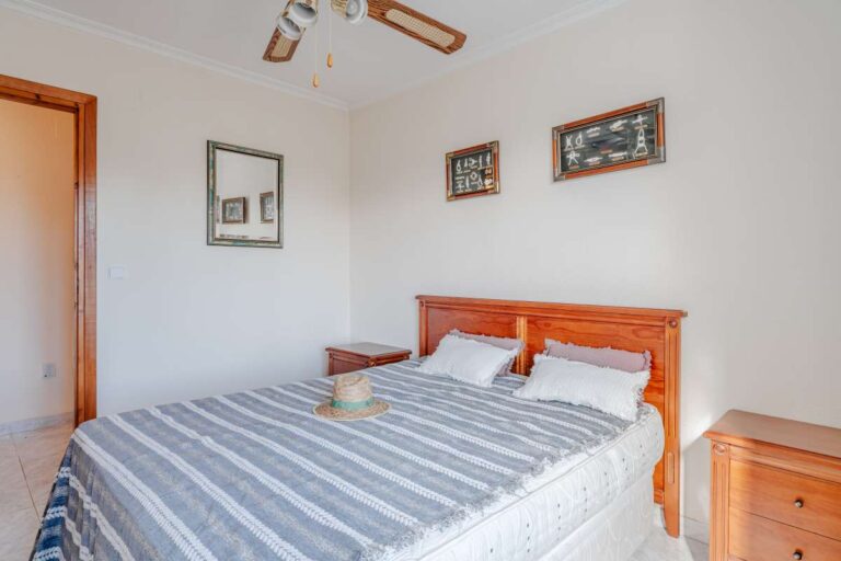 Double bedroom with wooden furniture and ceiling fan inside a Mediterranean villa in Calpe.