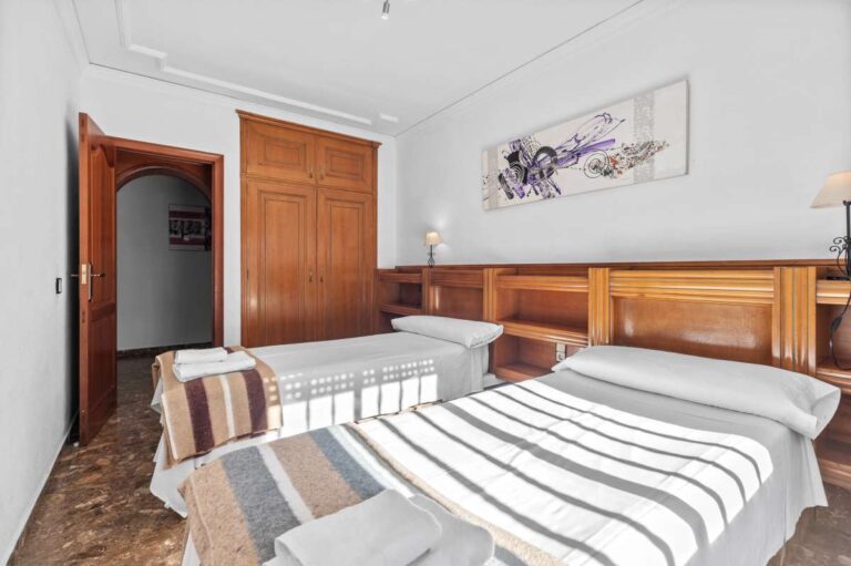Double bedroom with wooden wardrobe, tiled flooring and natural light inside a spacious villa in Calpe.
