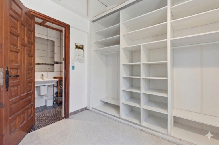 Dressing room inside a Mediterranean villa in Benissa Costa with built-in shelving, fitted storage and access to the en-suite bathroom