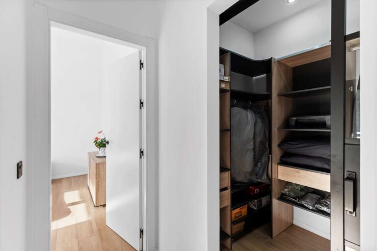 Dressing room inside a single-level modern villa in Santa Clara, Altea with fitted wardrobes, open shelving, bedroom access and contemporary finish