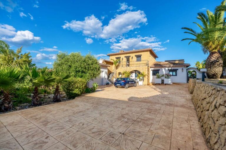Driveway and exterior of a premium coastal villa on the Benissa Costa with private parking, stone walling, Mediterranean planting and garage access