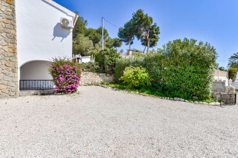 Driveway and garden area at a charming Benissa Coast villa with gravel parking, Mediterranean planting, stone walling and exterior access