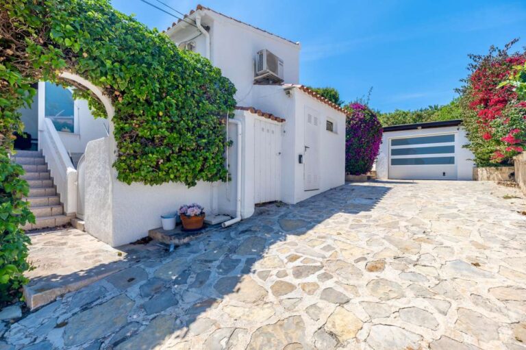 Driveway at a renovated single-level villa in Moraira with stone paving, private garage, entrance steps and Mediterranean planting