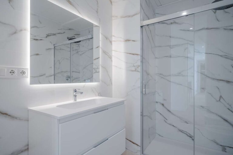 En-suite bathroom inside a modern second-line sea villa in La Calalga, Calpe with illuminated mirror, vanity unit and glass shower screen